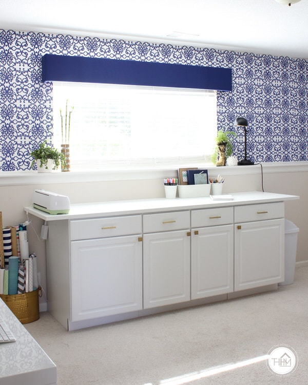 A craft office with renter-friendly wallpaper installed above a cabinet workspace