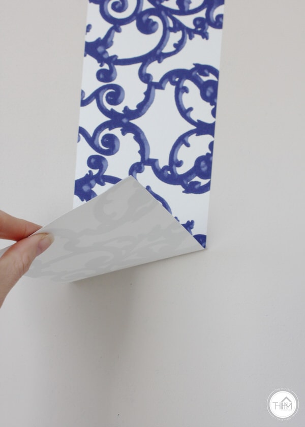A strip of wallpaper is easily removed from a blank wall 