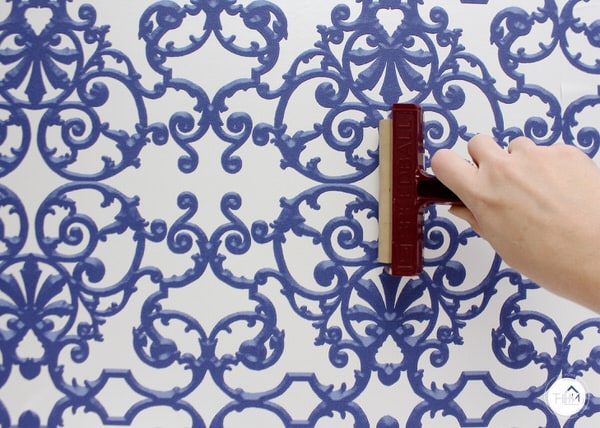 A brayer smoothes renter-friendly wallpaper to a wall