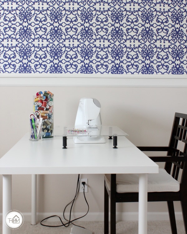 A home office with renter-friendly wallpaper installed above a table workspace