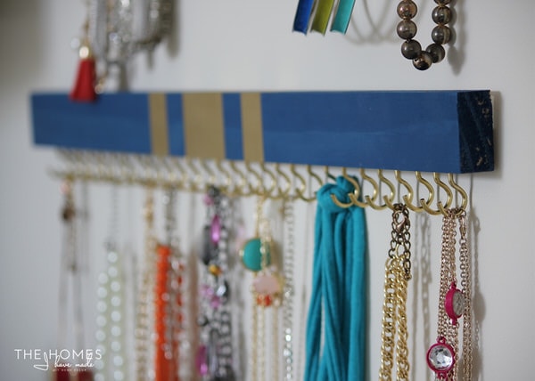 DIY Jewelry Organizer holding necklaces on gold hooks
