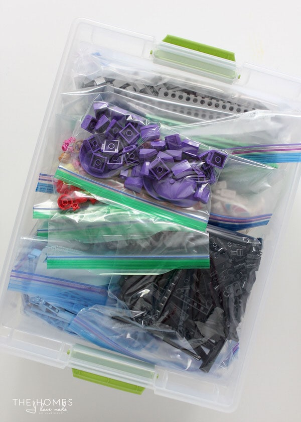 Overhead view of a clear opened bin containing Ziplock bags in which Lego pieces are organized by color