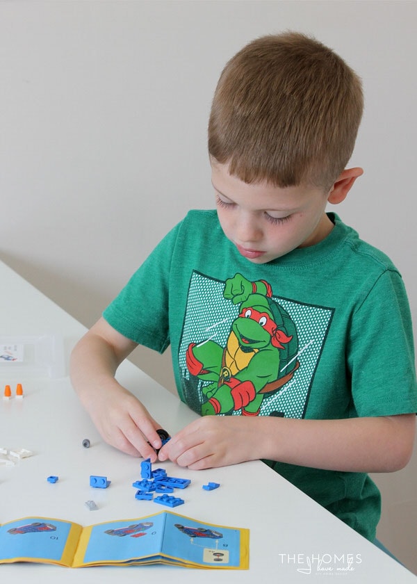 Photo of a child building a Lego set in front of an instructional manual
