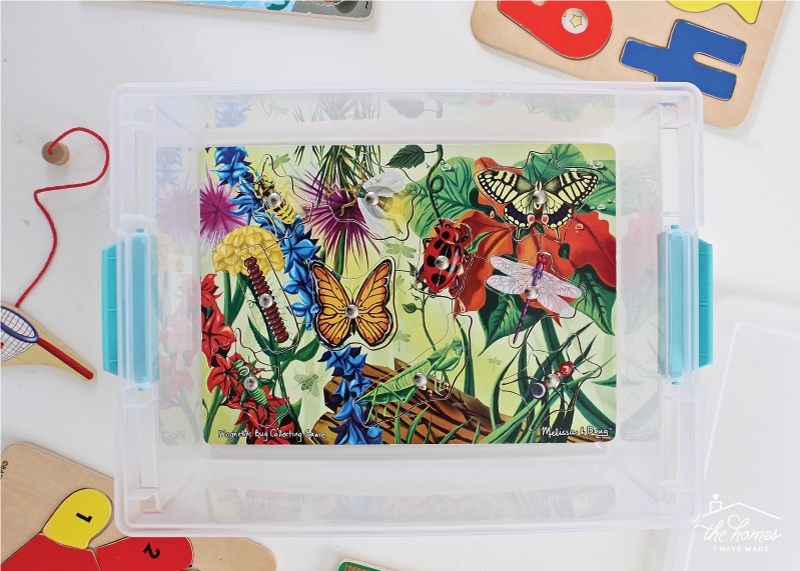 Overhead image of a wooden kid puzzle inside an open clear container 