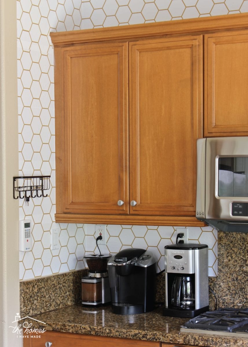 Kitchen with brown cabinets and white hexagon peel-and-stick wallpaper backsplash