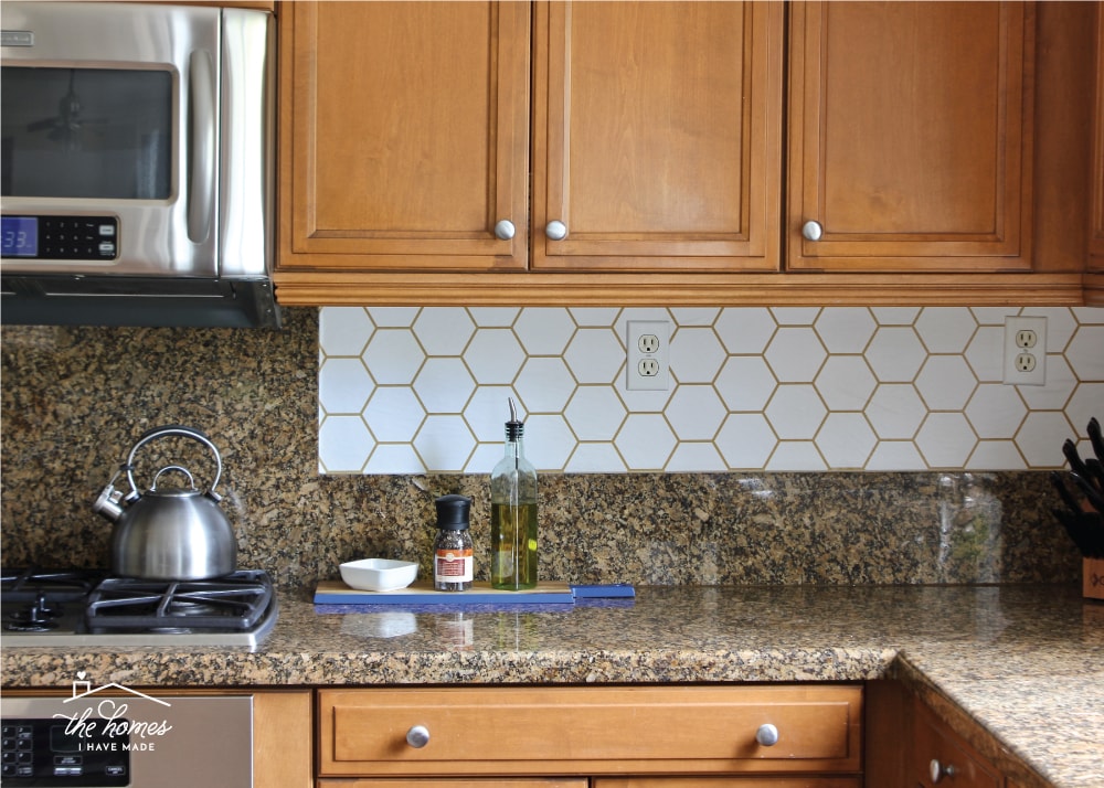 Kitchen with brown cabinets and white hexagon peel-and-stick wallpaper backsplash