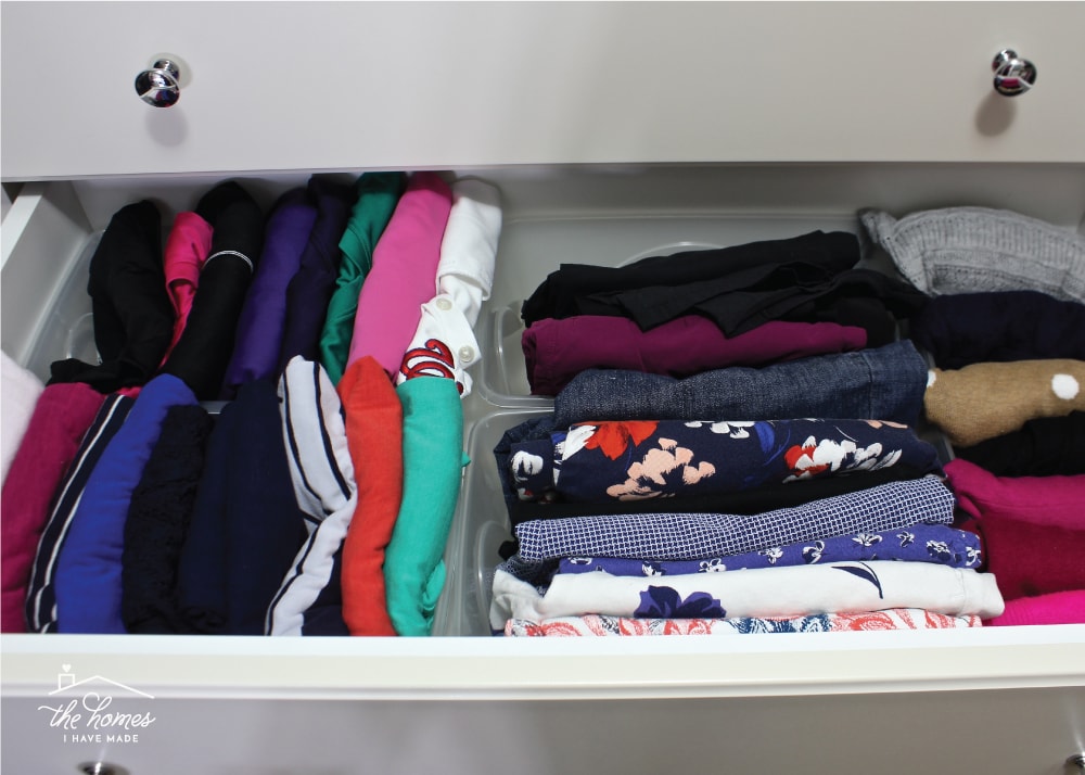 Clothes organized in a drawer with plastic shoe boxes.