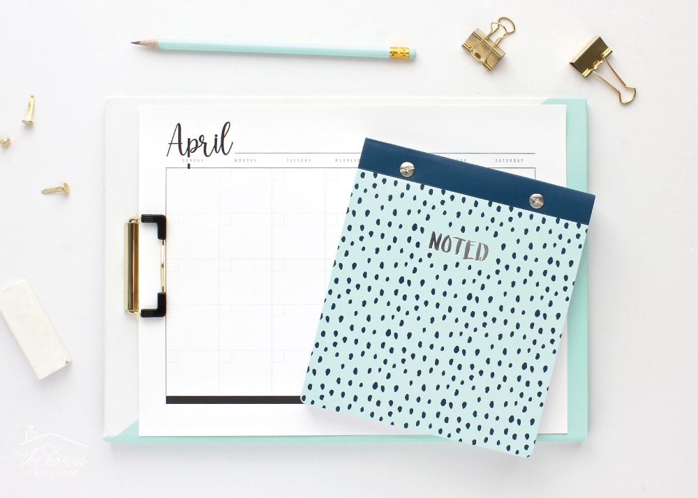 Blank printable monthly calendar shown with a light-blue notebook.