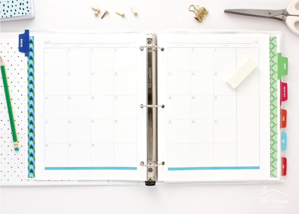 Two-page blank monthly calendar spread in a colorful binder