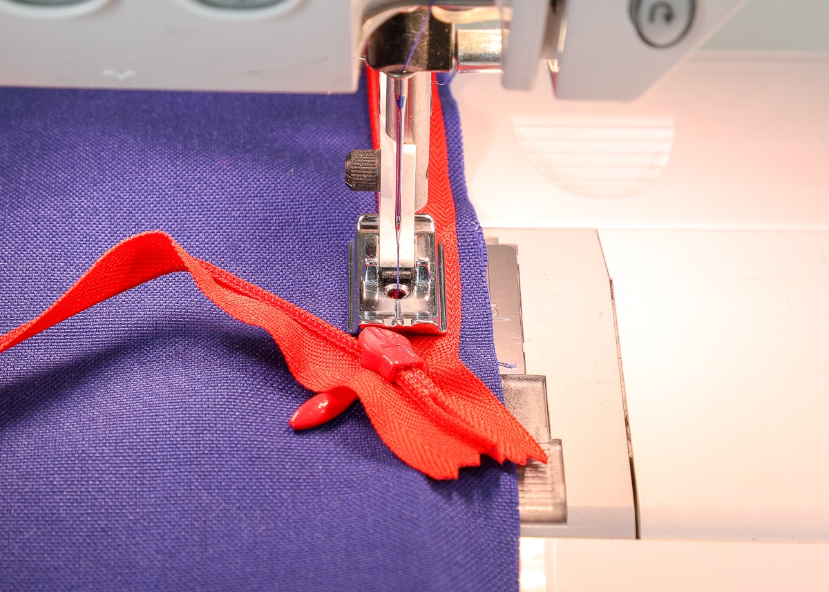 The fabric and invisible zipper are fed through a sewing machine