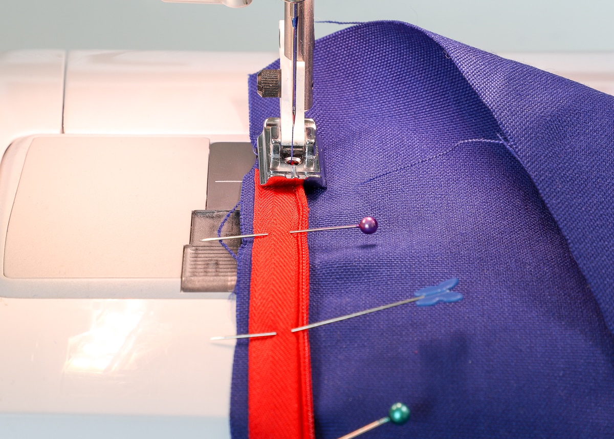 the zipper and fabric are fed through the sewing machine