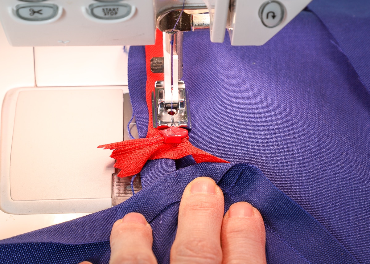 the zipper and fabric are fed through the sewing machine