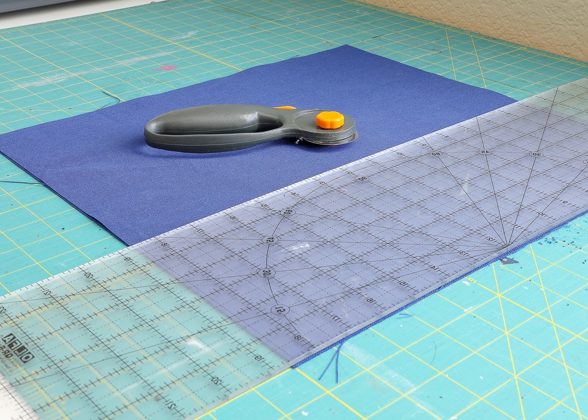 a piece of fabric laying on top of a cutting mat with a ruler and rotary cutter.