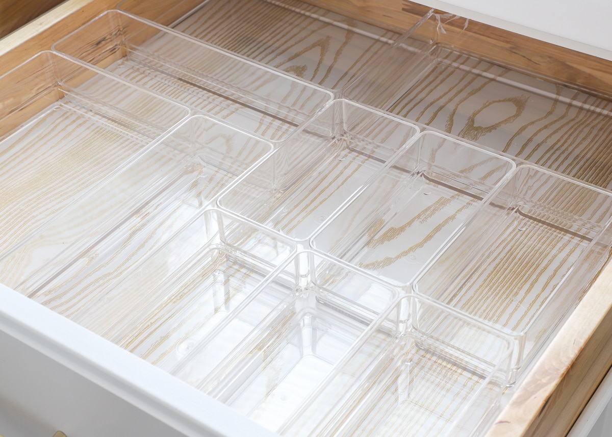 Clear acrylic drawer organizers of varying sizes organized in an office drawer