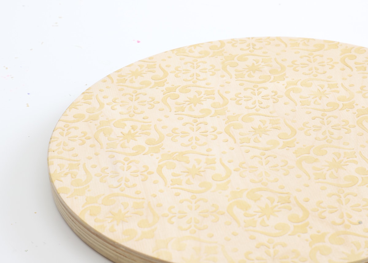 A wooden stool stenciled with Cricut Stencil Vinyl and gold paint