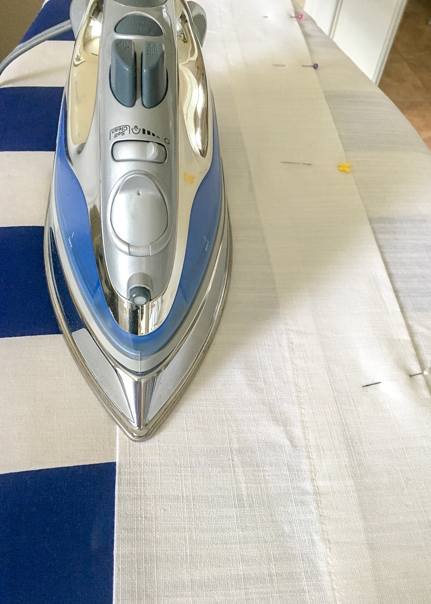 ironing a curtain hem flat on top of an ironing board