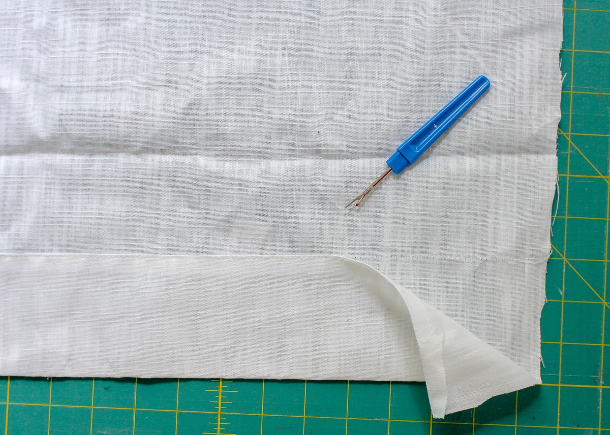 8 inches of the bottom hem of a curtain panel is removed with a seam ripper