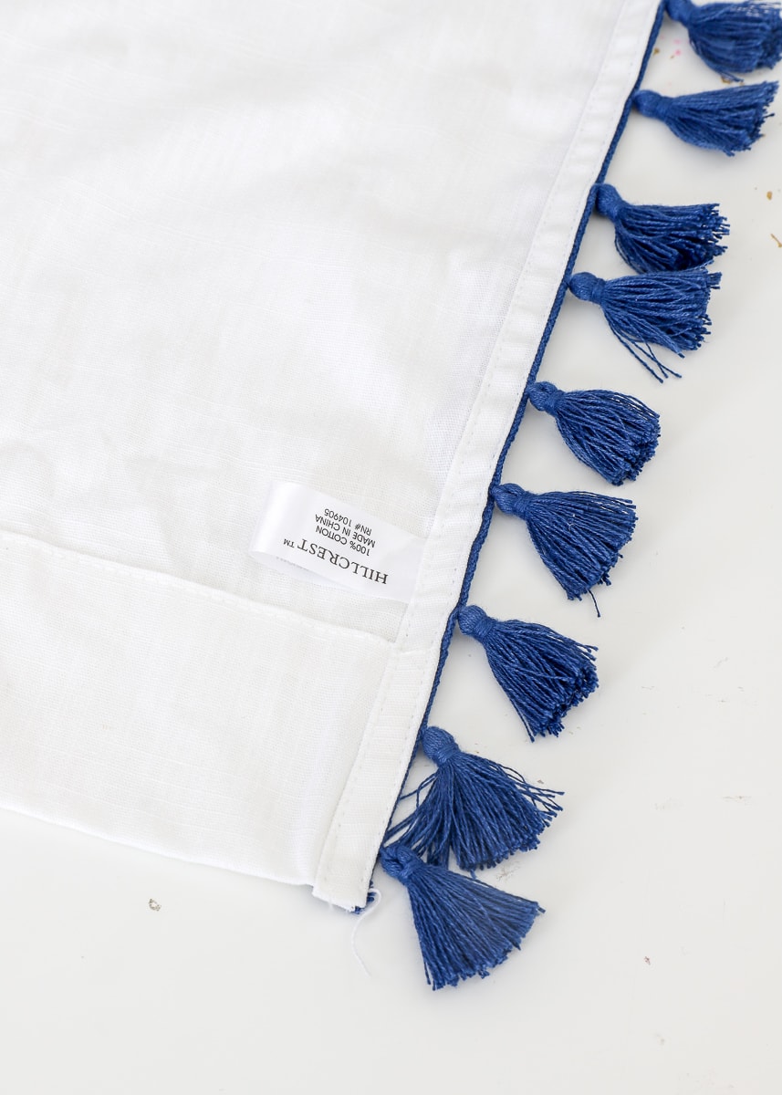 A pom-pom curtain trim is shown on top of a finished hem