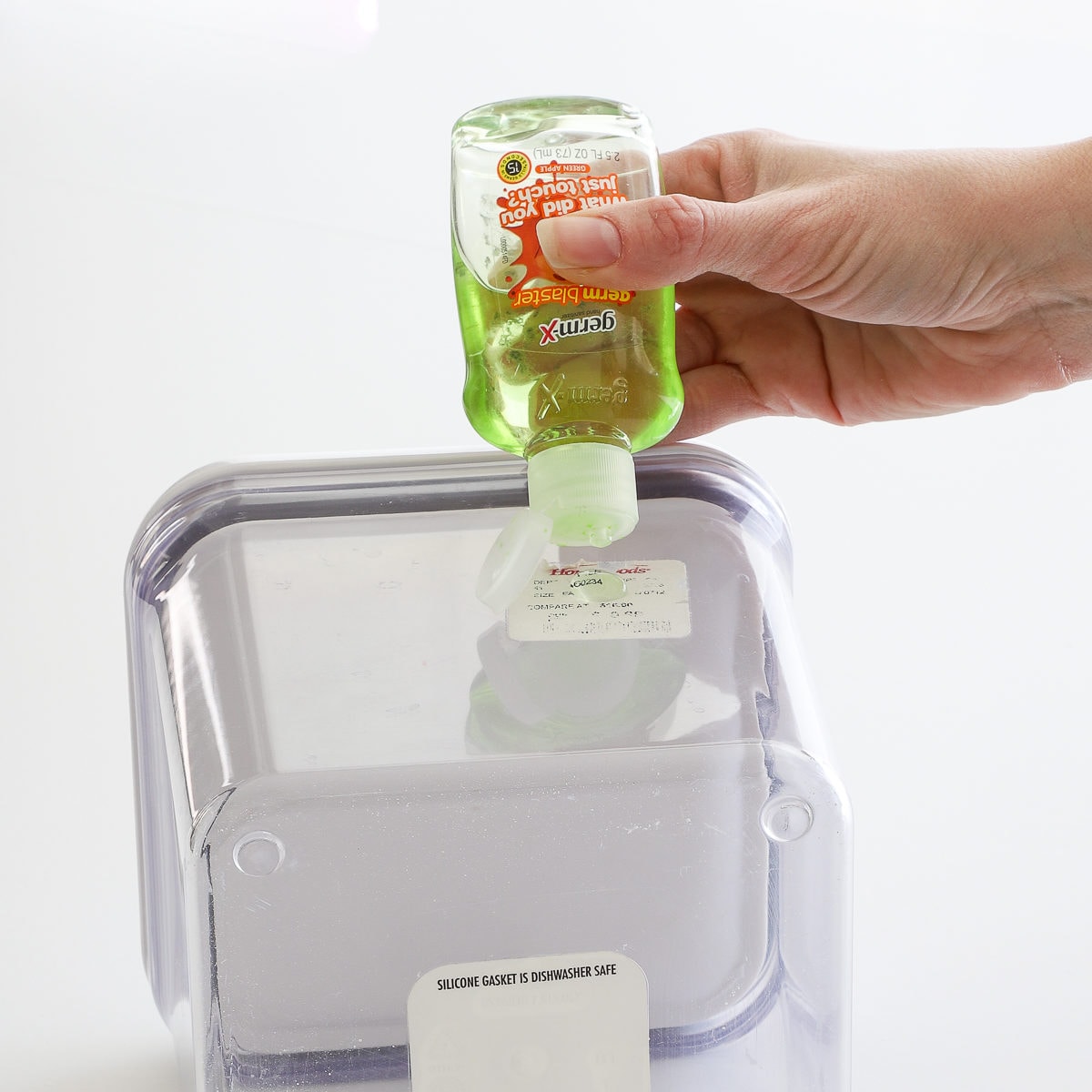 Hand applying hand sanitizer on a stubborn paper label to remove it