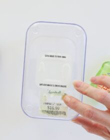 Finger nail scraping up a white paper label off a food canister after covering it in hand sanitizer