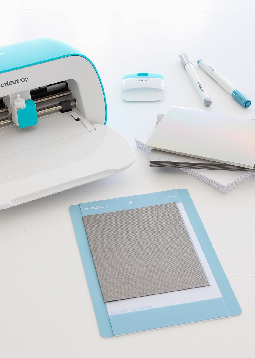 A folded card is lined with the pre-printed lines on the Cricut Joy Card Mat.