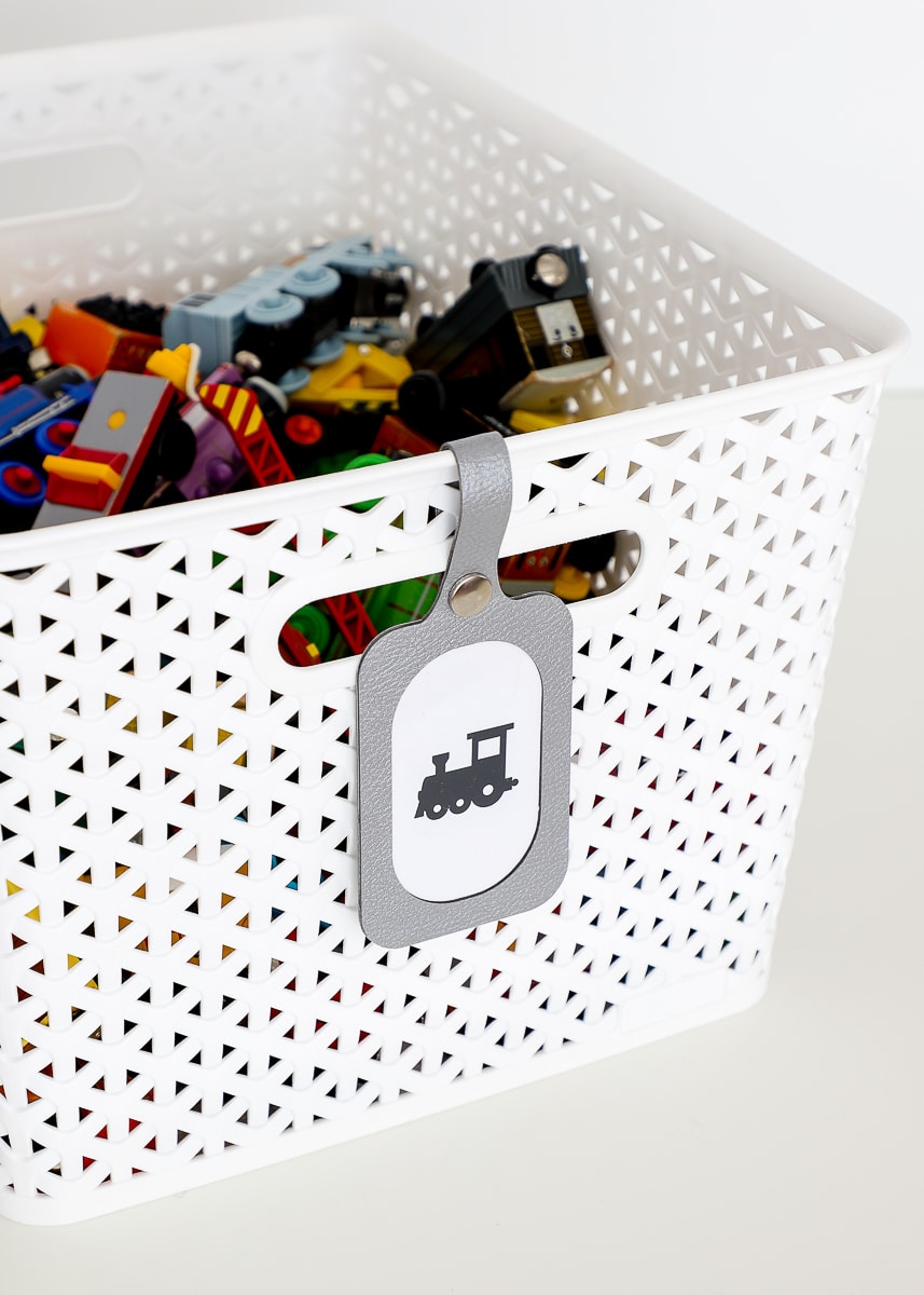 Luggage tag label on a white basket filled with toy trains