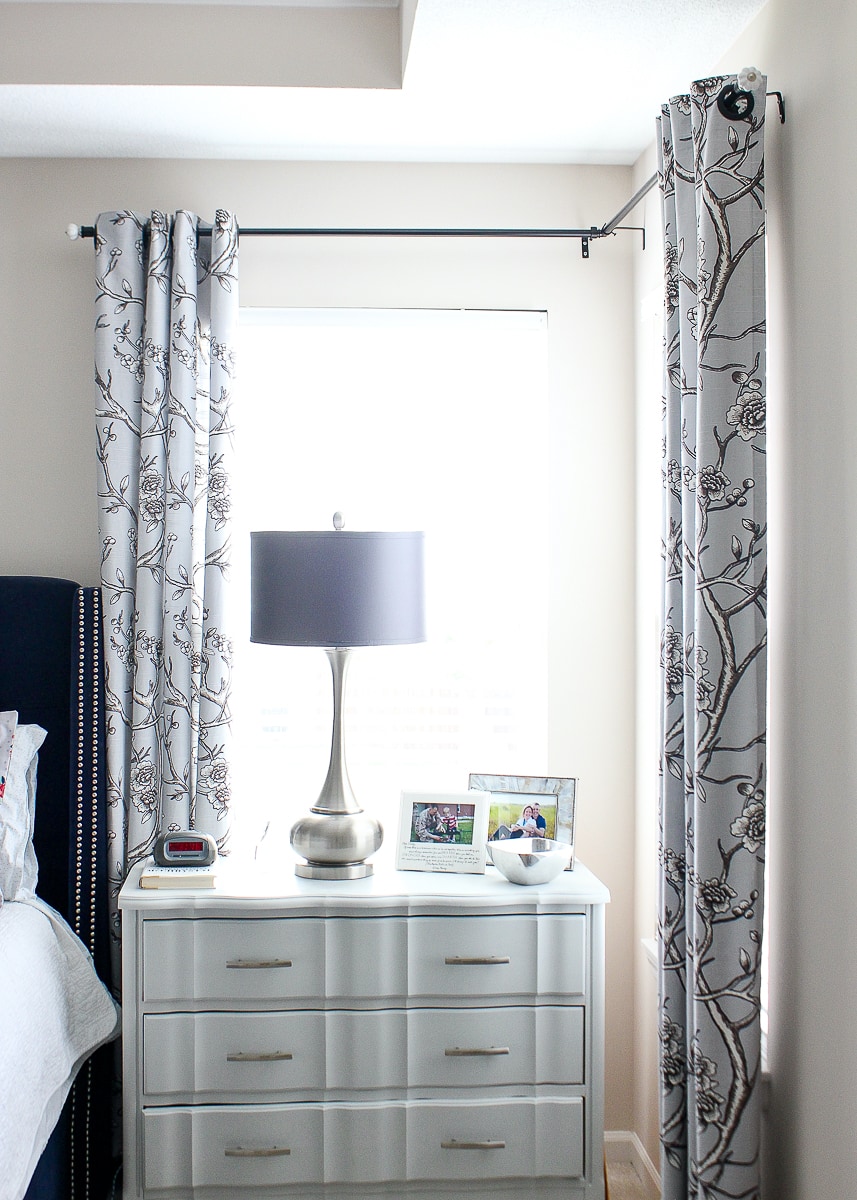 A corner window with curtains in a master bedroom