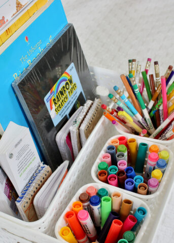 Markers and art supplies organized into white baskets