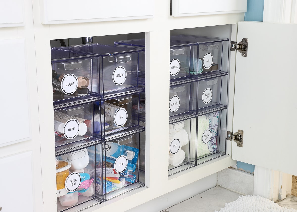 Clear stacking drawers with labels in a bathroom cabinet