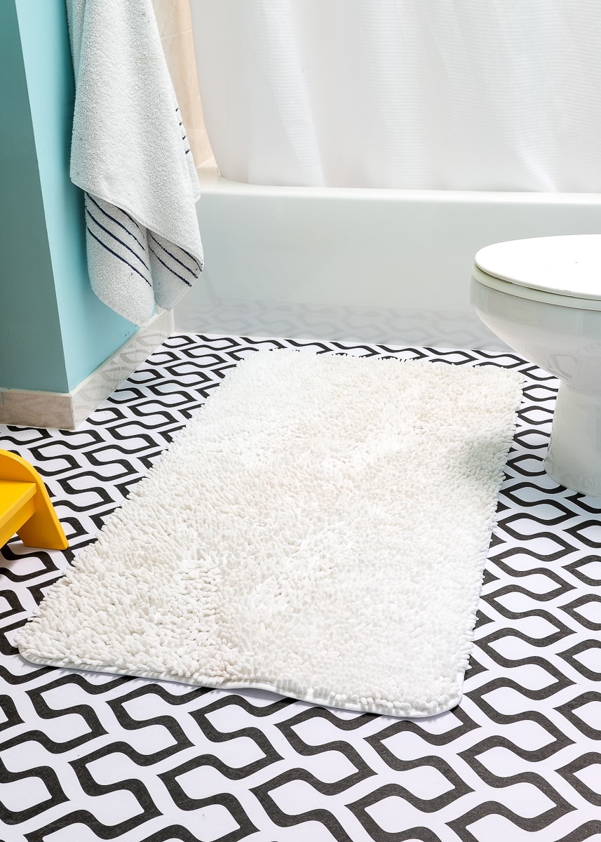 White bath mat over floor covered in peel and stick wallpaper