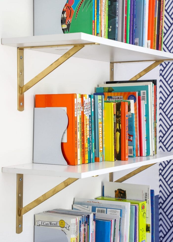 White shelf with gold brackets, white bookends and kids books.