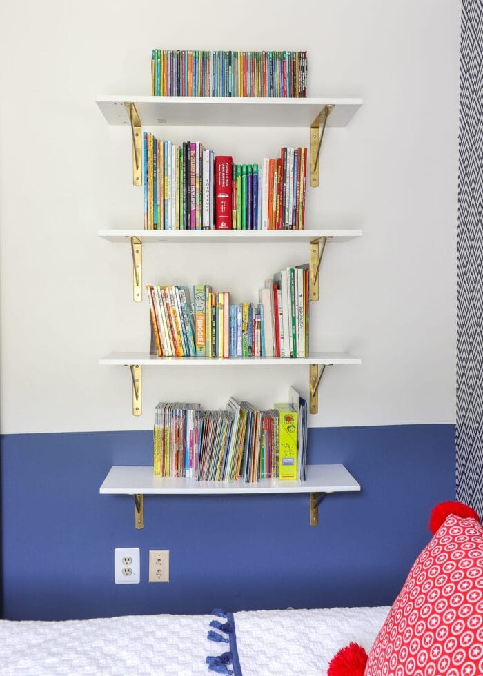 White shelf with gold brackets, white bookends and kids books.