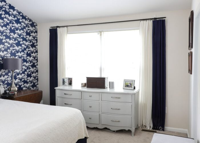 Bedroom with blue wallpaper and a curtain rod hung with Command Hooks