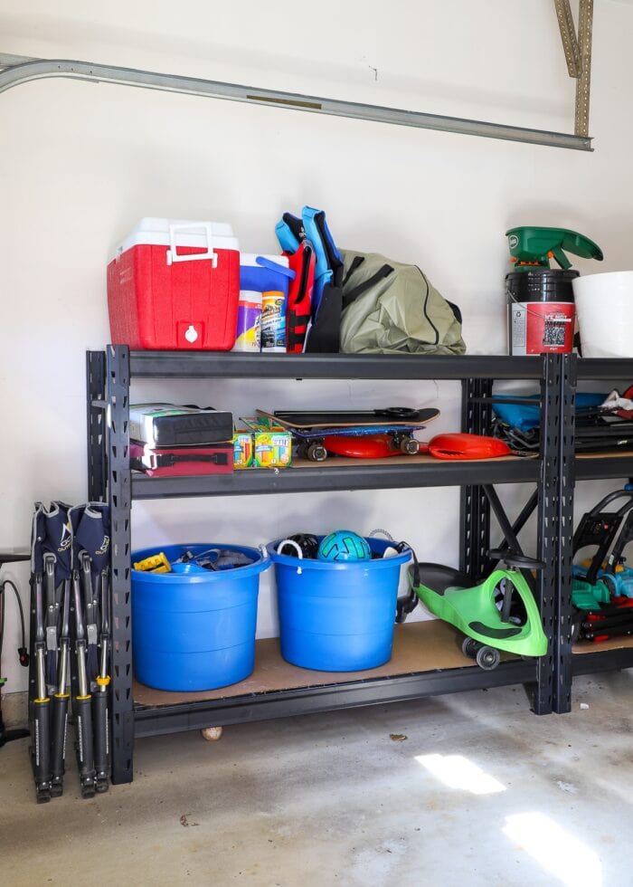 Garage with black metal shelving loaded with toys and bikes.