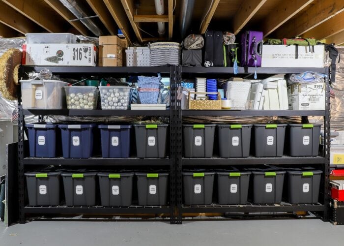 Horizontal picture of black metal storage shelves loaded with bins, baskets, and boxes.