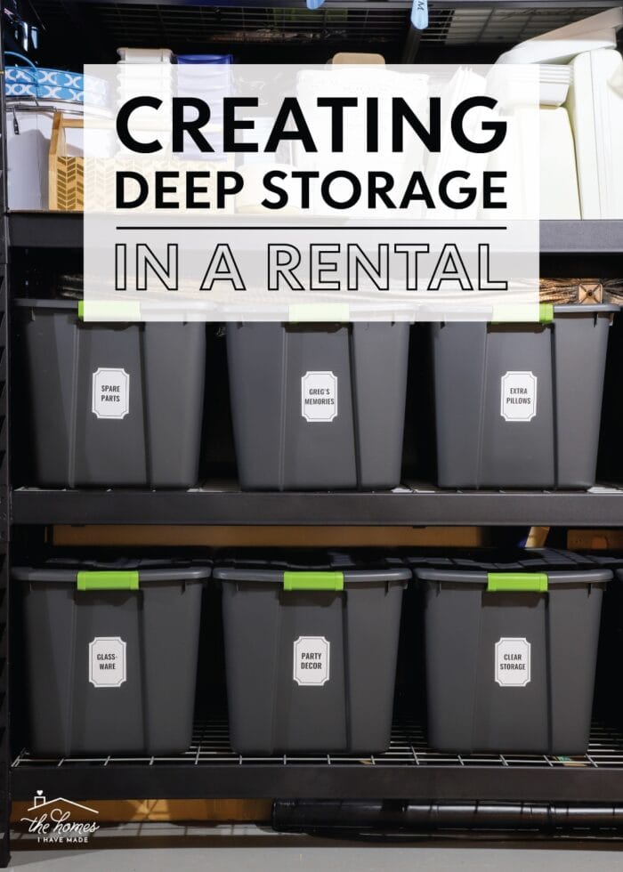 Vertical picture of grey storage bins with white labels on a black metal shelf in rental deep storage.