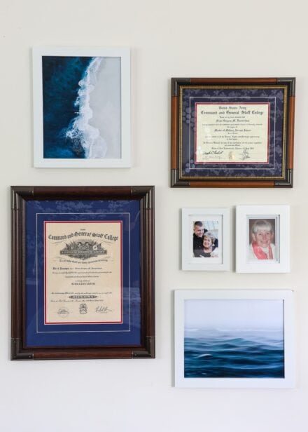 Small gallery wall with white and wood frames and ocean artwork.