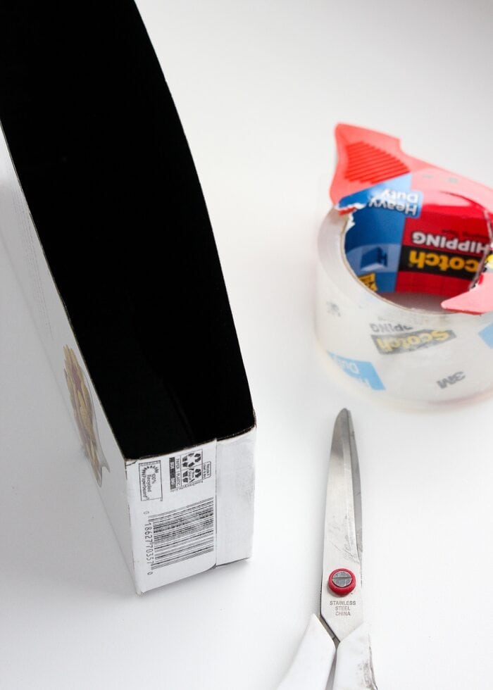 A cut-down cereal box shown with scissors and tape.