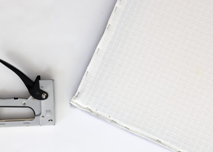 Staple gun shown within lining fabric on a bench cover.