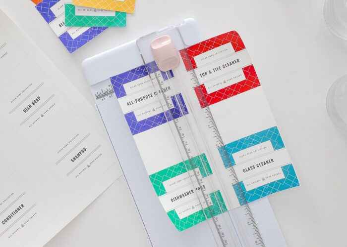 Colorful printable cleaning labels being cut with a paper trimmer.