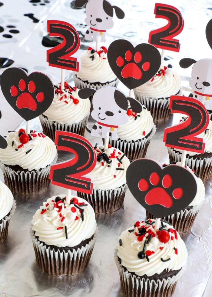 Chocolate cupcakes with white frosting and adorable puppy dog cake toppers made from paper.