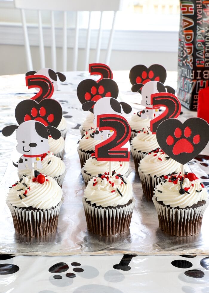Chocolate cupcakes with white frosting and adorable puppy dog cake toppers made from paper.