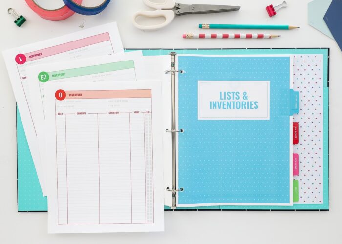 Printable Moving Binder opened on a white desk with the Lists and Inventories section showing.