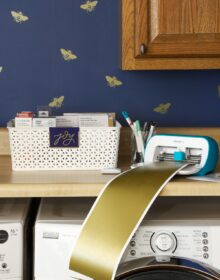 Navy blue laundry room with gold bee vinyl decals made with a Cricut, shown with a Cricut Joy.