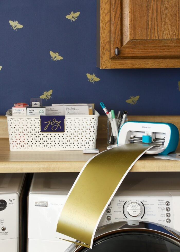 Navy blue laundry room with gold bee vinyl decals made with a Cricut, shown with a Cricut Joy.