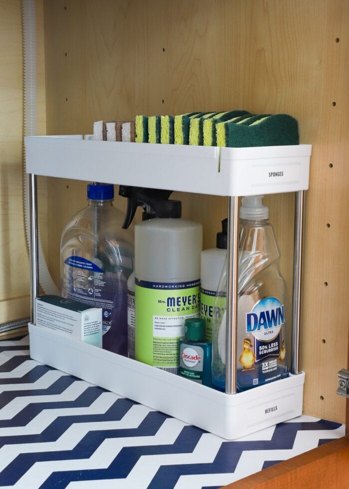 Cleaning supplies in a vertical organizer underneath kitchen sink.