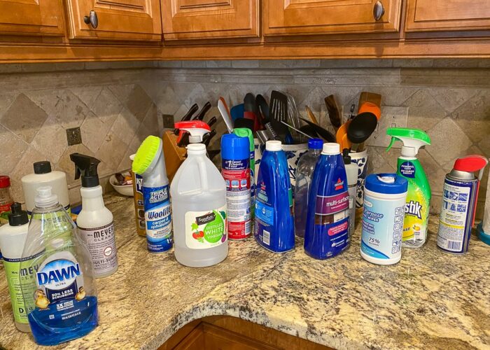 An assortment of cleaning supplies on a kitchen countertop.