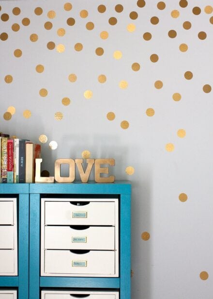 Gold polka dot wall decals behind a turquoise shelf.
