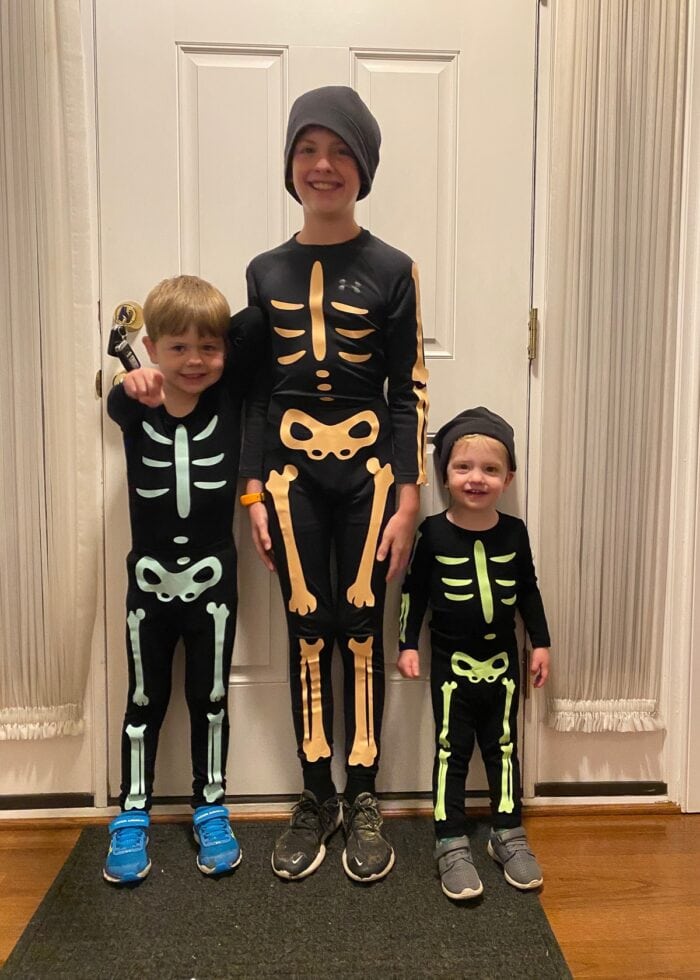 Three boys with glow-in-the-dark skeleton bones on black outfits.