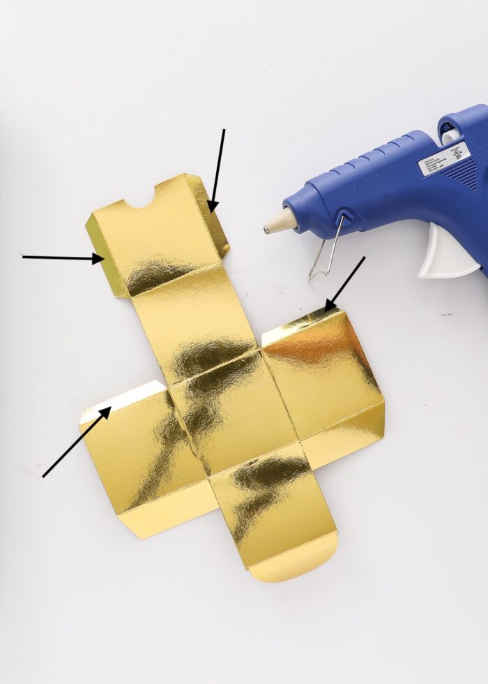 3D box cut from gold foil Kraft board shown with a hot glue gun.
